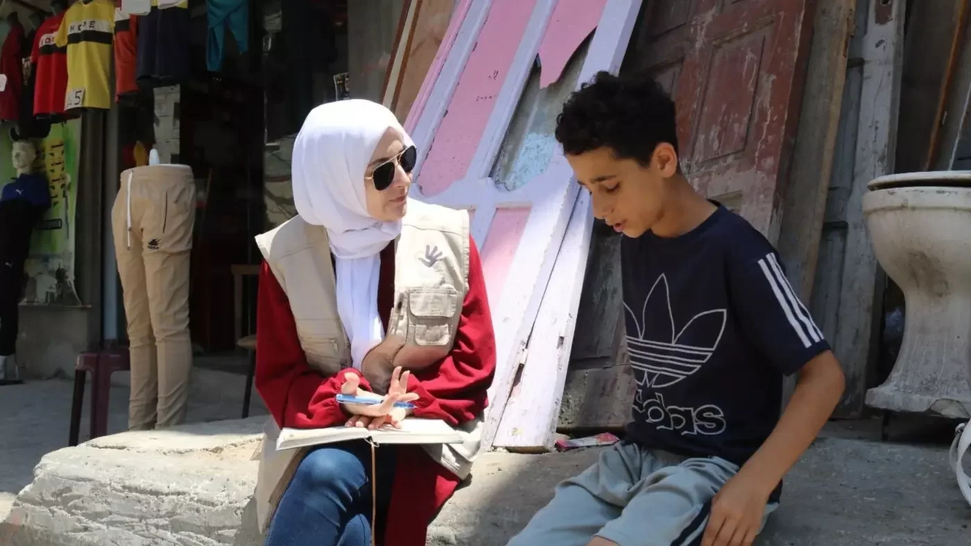 Maha Hussaini interviews a Palestinian boy in Gaza in June 2023